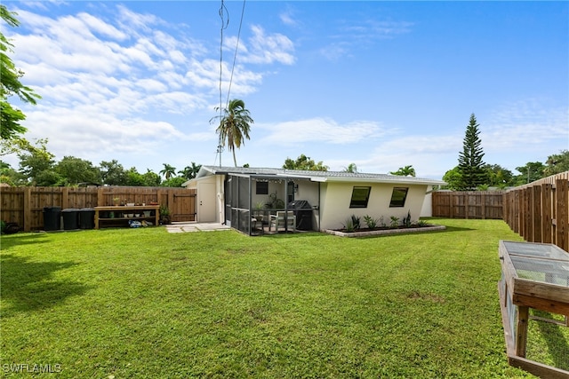 back of property with a sunroom and a lawn