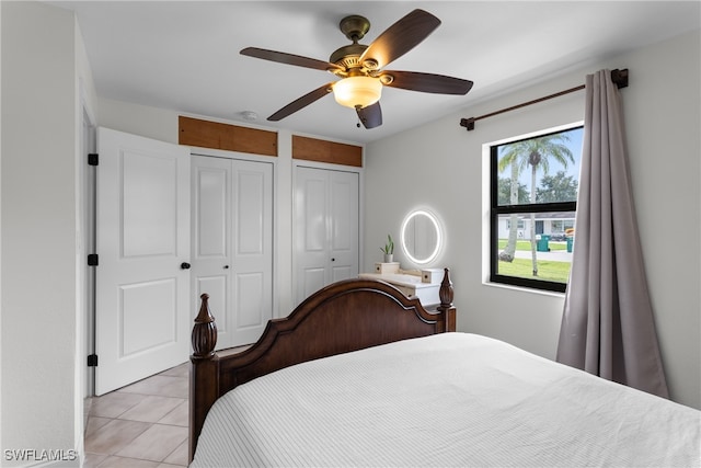 bedroom featuring two closets, light tile patterned flooring, and ceiling fan