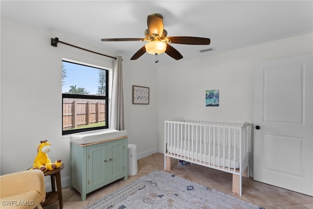 tiled bedroom with ceiling fan and a nursery area