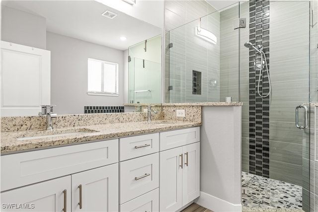 bathroom with a shower with shower door and vanity