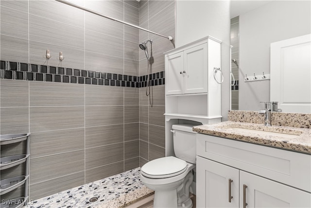 bathroom with toilet, vanity, and a tile shower