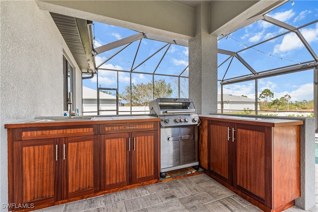 view of patio with a lanai, a wet bar, a grill, and an outdoor kitchen