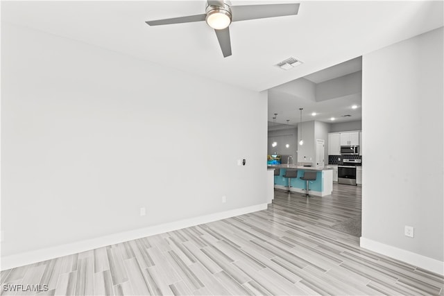 empty room with ceiling fan, sink, and light wood-type flooring