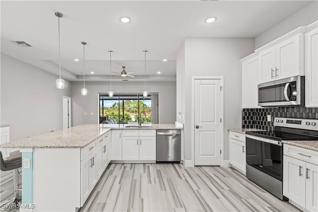 kitchen with ceiling fan, decorative light fixtures, appliances with stainless steel finishes, and white cabinetry