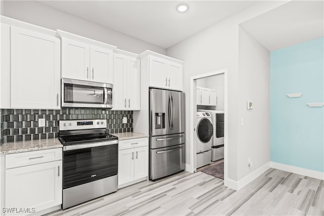 kitchen featuring white cabinets, appliances with stainless steel finishes, backsplash, light wood-type flooring, and light stone counters