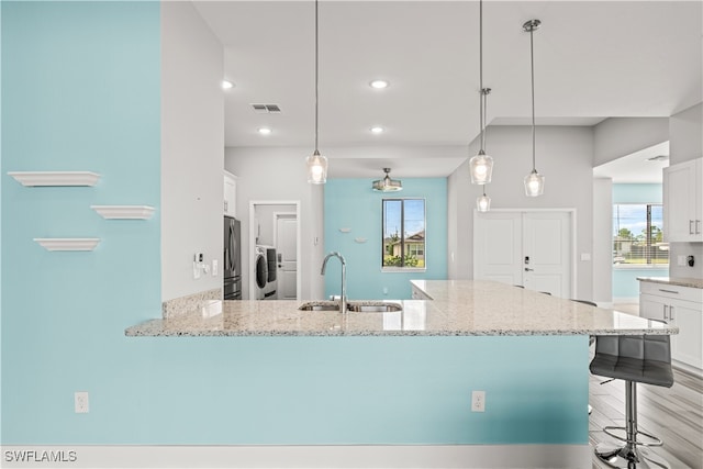 kitchen with a kitchen breakfast bar, white cabinetry, decorative light fixtures, and sink