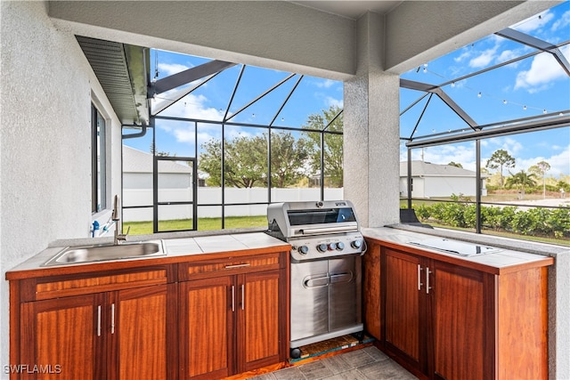 view of patio with grilling area, an outdoor kitchen, a lanai, and sink