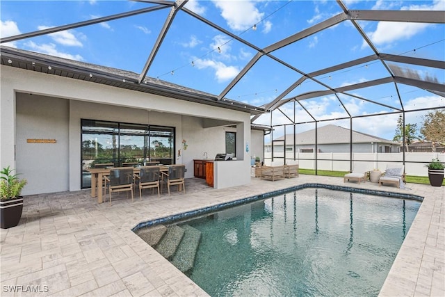 view of pool featuring exterior kitchen, a lanai, and a patio area