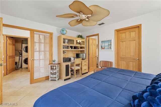 tiled bedroom featuring stacked washer / dryer and ceiling fan