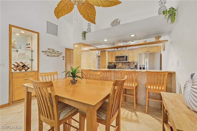 dining area featuring a towering ceiling and light tile patterned flooring