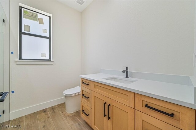 bathroom with vanity, wood-type flooring, and toilet