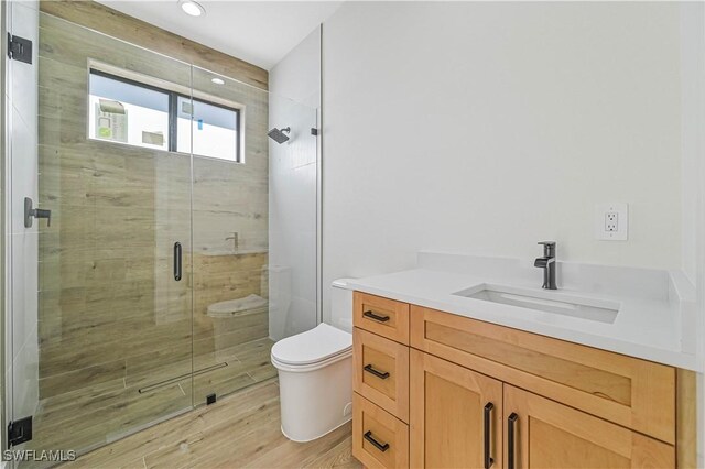 bathroom with toilet, walk in shower, vanity, and wood-type flooring