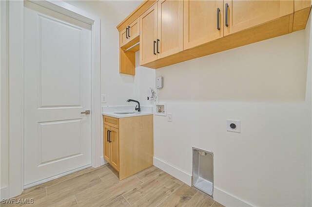 laundry area with sink, hookup for an electric dryer, light wood-type flooring, washer hookup, and cabinets