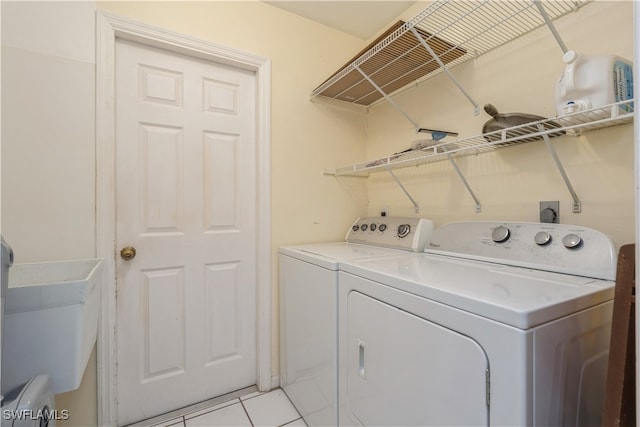 clothes washing area with light tile patterned flooring and separate washer and dryer