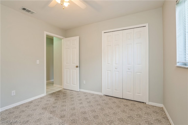 unfurnished bedroom with ceiling fan, multiple windows, a closet, and light colored carpet