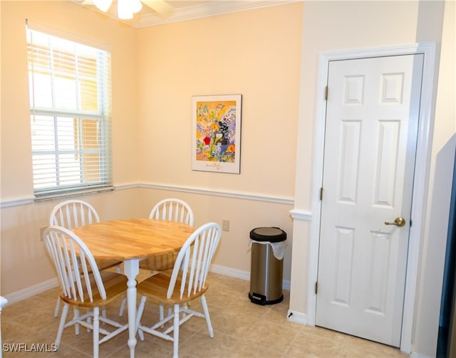 tiled dining space featuring ceiling fan and ornamental molding