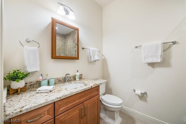 bathroom featuring toilet, baseboards, and vanity