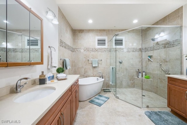 bathroom featuring visible vents, a stall shower, a soaking tub, and vanity