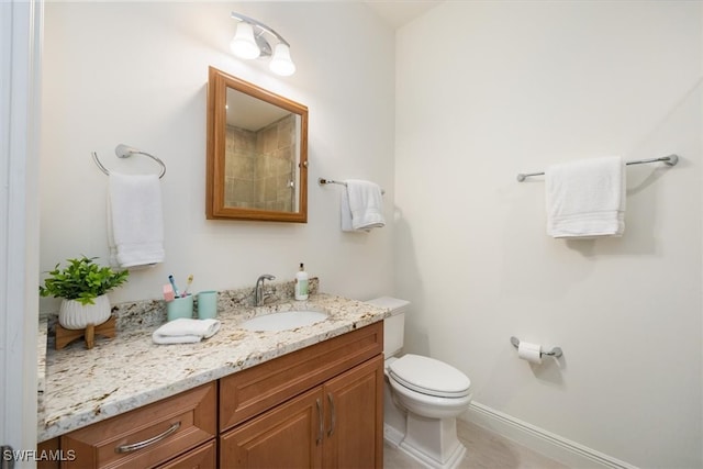 bathroom with baseboards, vanity, and toilet