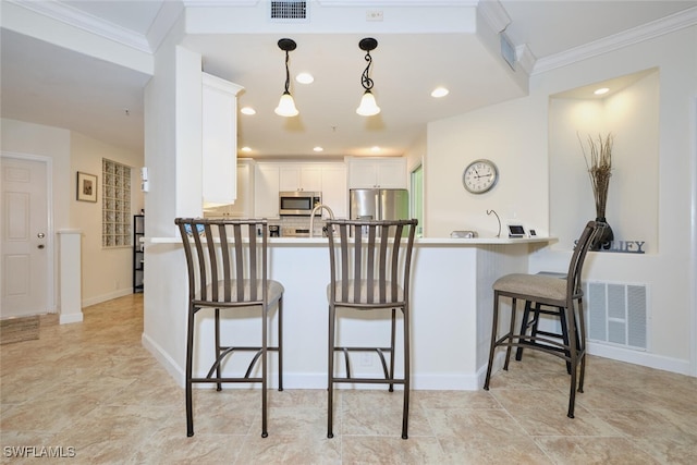 kitchen with kitchen peninsula, hanging light fixtures, appliances with stainless steel finishes, white cabinetry, and crown molding