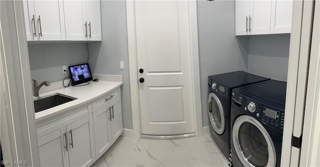 clothes washing area featuring cabinets, washer and clothes dryer, and sink