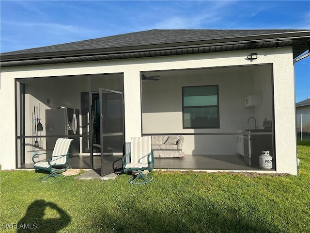 rear view of property with a lawn and a sunroom