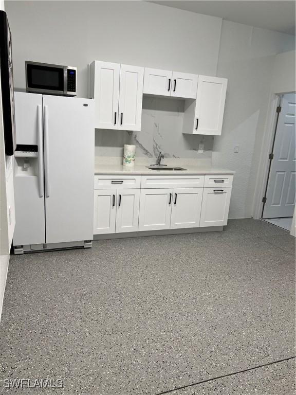 kitchen featuring tasteful backsplash, sink, white fridge with ice dispenser, and white cabinets