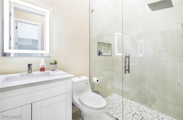 bathroom featuring vanity, toilet, and a shower with shower door