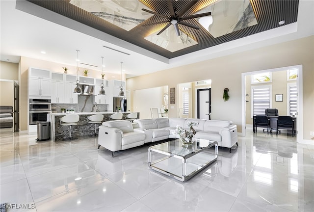 living room with a tray ceiling and ceiling fan