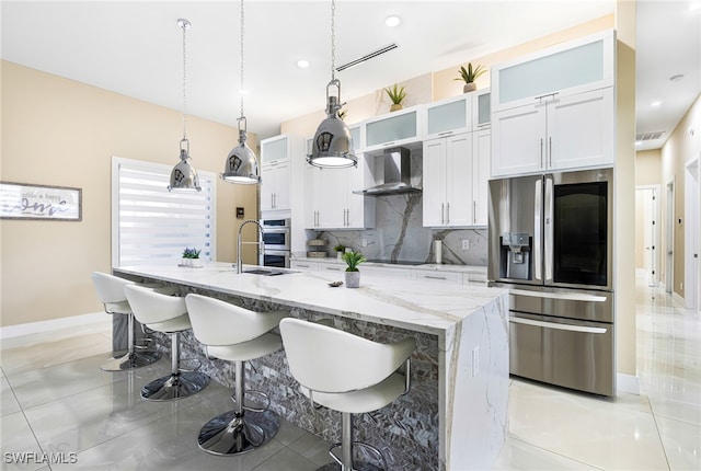 kitchen with white cabinets, light stone countertops, a kitchen bar, wall chimney exhaust hood, and stainless steel appliances