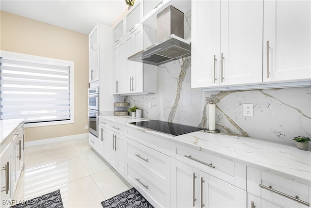 kitchen featuring black electric stovetop, range hood, light stone countertops, light tile patterned flooring, and white cabinets