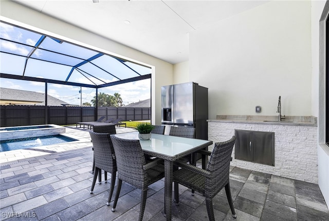 view of patio featuring an in ground hot tub, a lanai, sink, and area for grilling