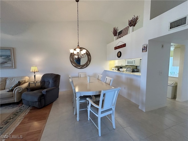 dining space with a chandelier, high vaulted ceiling, and light wood-type flooring