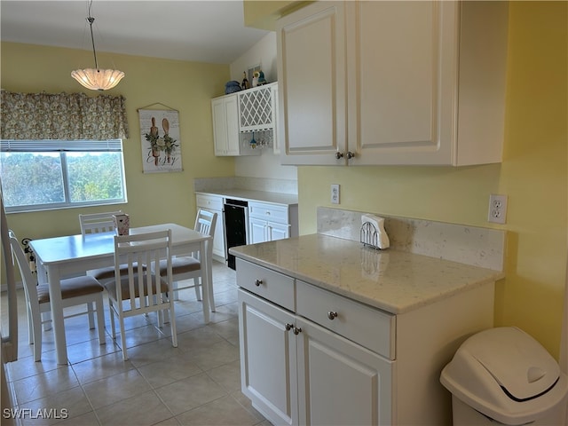 kitchen with white cabinetry, light stone countertops, light tile patterned flooring, and pendant lighting