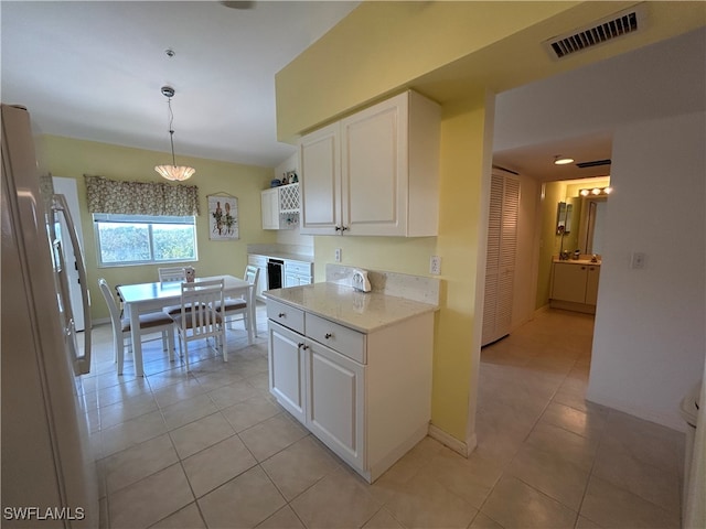 kitchen featuring hanging light fixtures, light tile patterned floors, white refrigerator, and white cabinets