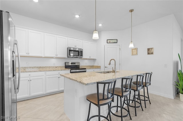 kitchen with hanging light fixtures, a center island with sink, sink, white cabinetry, and appliances with stainless steel finishes