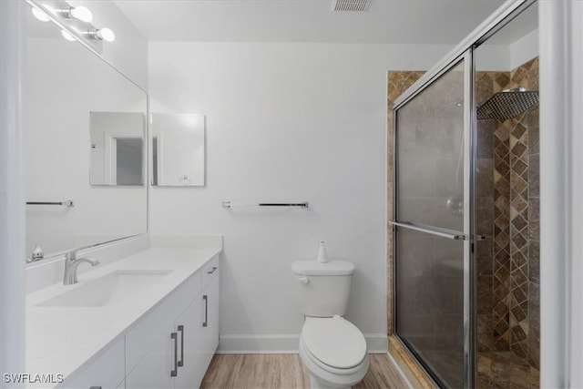 bathroom featuring toilet, vanity, a shower with door, and hardwood / wood-style flooring