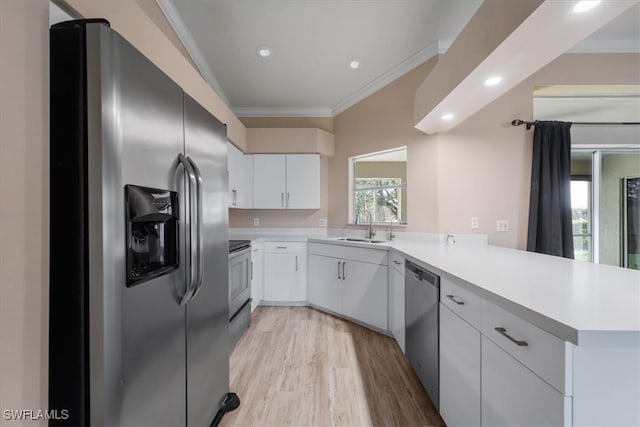 kitchen featuring sink, stainless steel appliances, kitchen peninsula, white cabinets, and ornamental molding