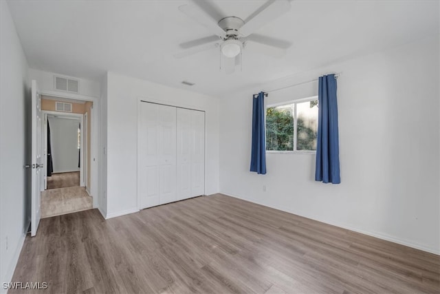 unfurnished bedroom with ceiling fan, a closet, and light wood-type flooring