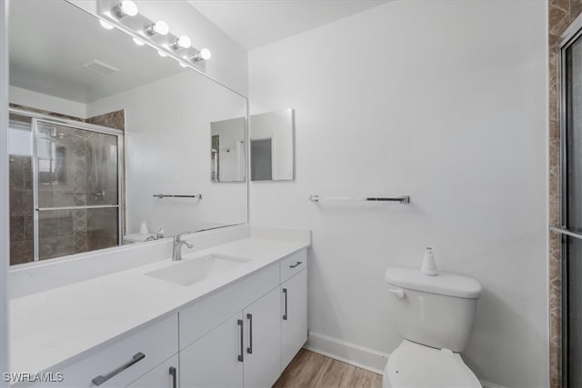 bathroom featuring vanity, toilet, wood-type flooring, and a shower with door