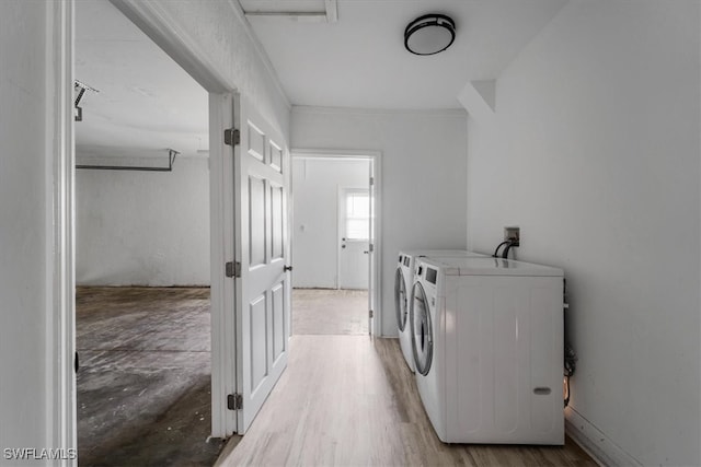 laundry room featuring light hardwood / wood-style flooring, ornamental molding, and washing machine and clothes dryer