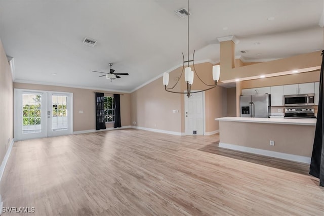 unfurnished living room featuring french doors, ceiling fan with notable chandelier, vaulted ceiling, ornamental molding, and light hardwood / wood-style floors