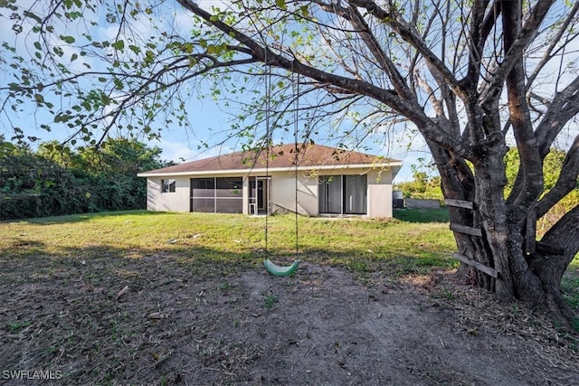 rear view of property featuring a sunroom and a lawn