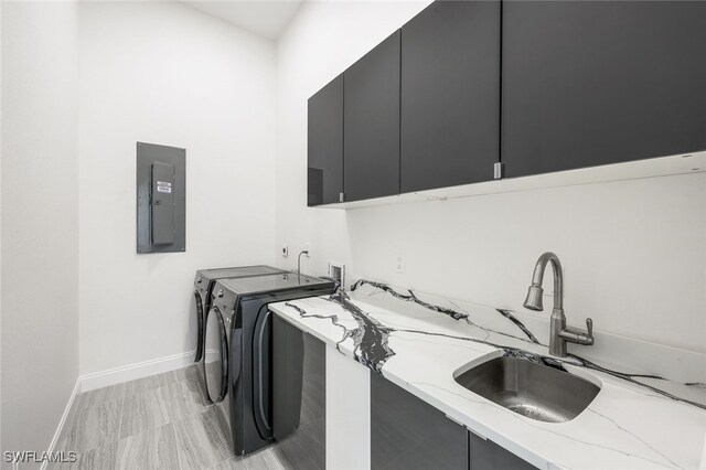 washroom featuring washer and clothes dryer, light hardwood / wood-style flooring, sink, cabinets, and electric panel