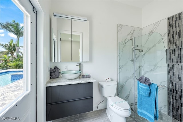 bathroom featuring vanity, a tile shower, and toilet