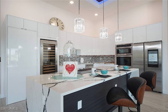 kitchen with wine cooler, appliances with stainless steel finishes, pendant lighting, and white cabinets