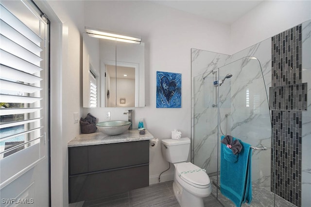 bathroom with toilet, vanity, and a shower with door