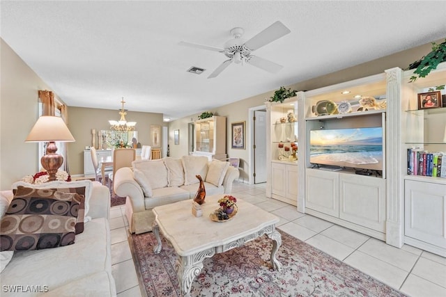 living room with ceiling fan with notable chandelier, light tile patterned floors, and a textured ceiling