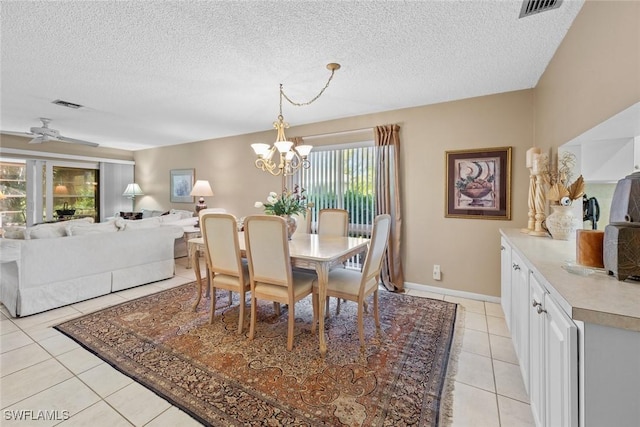 tiled dining space featuring a textured ceiling and ceiling fan with notable chandelier