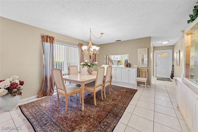 dining area with a textured ceiling, a notable chandelier, and light tile patterned flooring